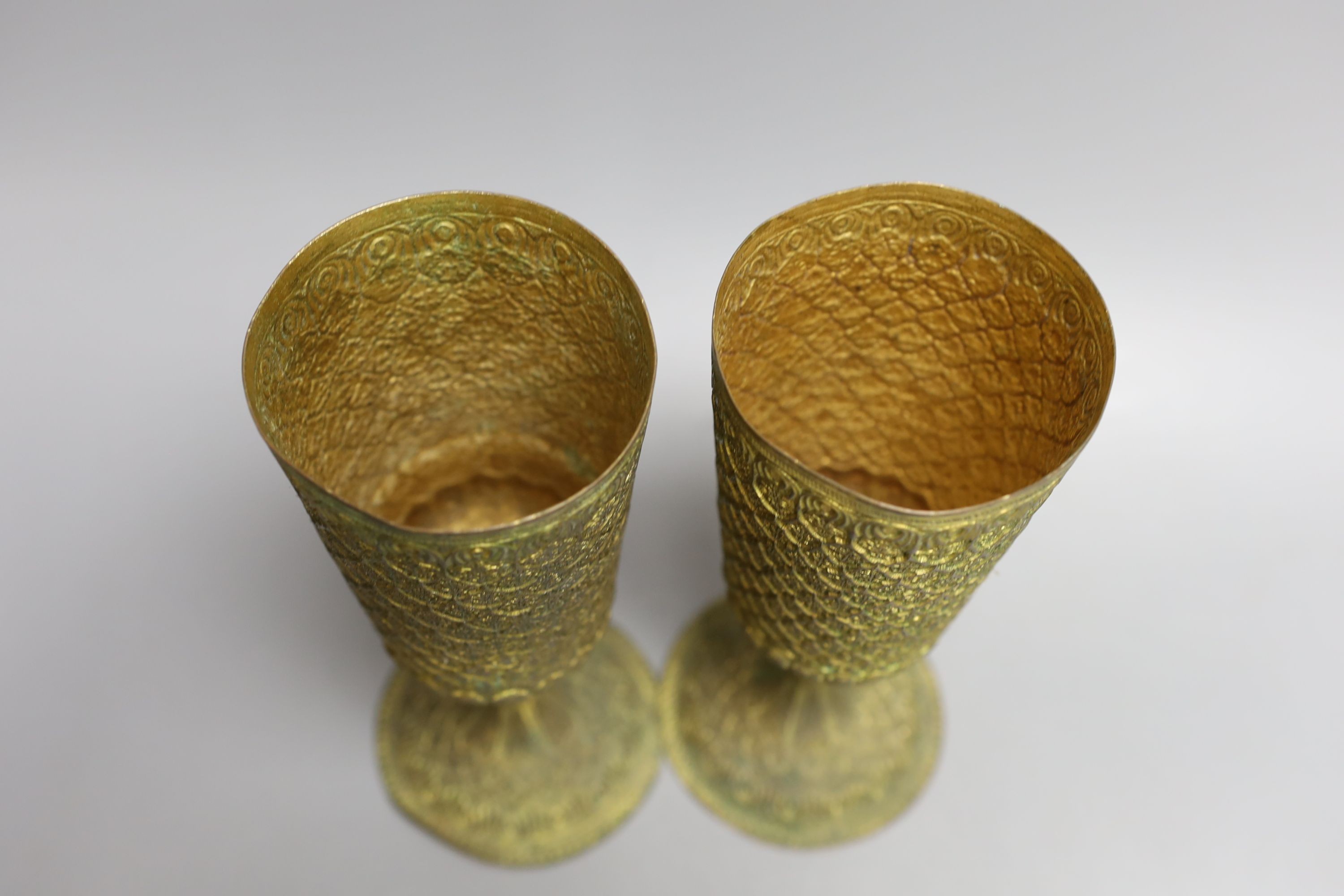 A pair of Middle Eastern repousse gilt metal goblets, 22cms high.